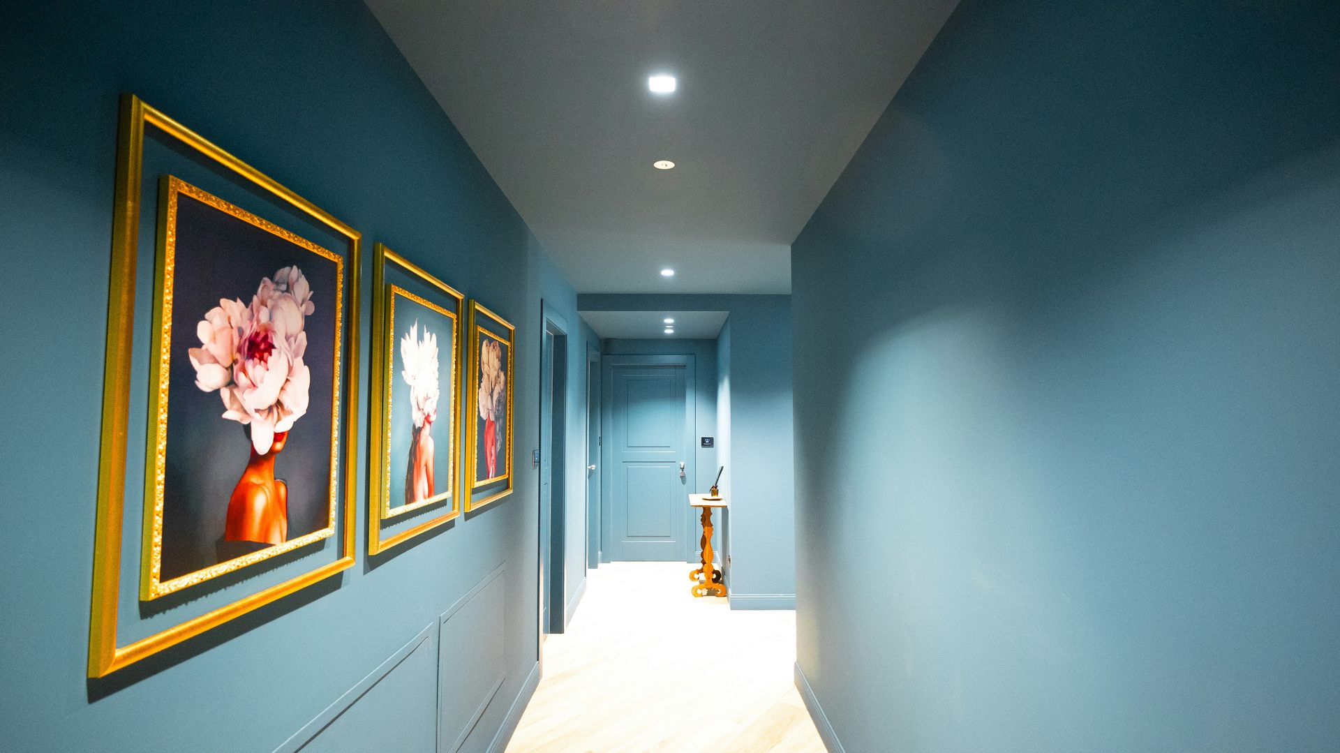 Hallway with blue walls and framed floral artwork