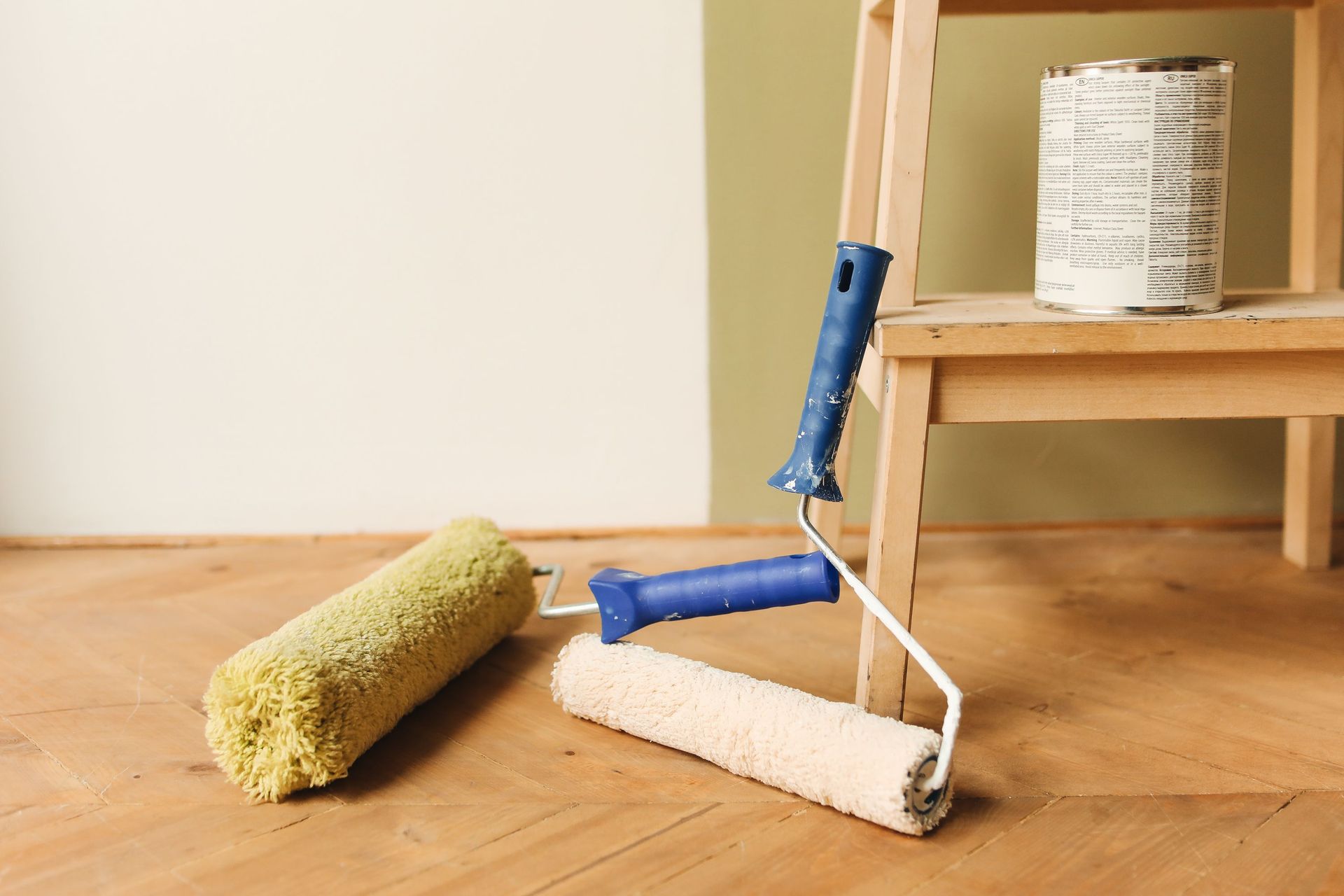 Paint rollers on wooden floor surface next to a can, ready for home renovation.